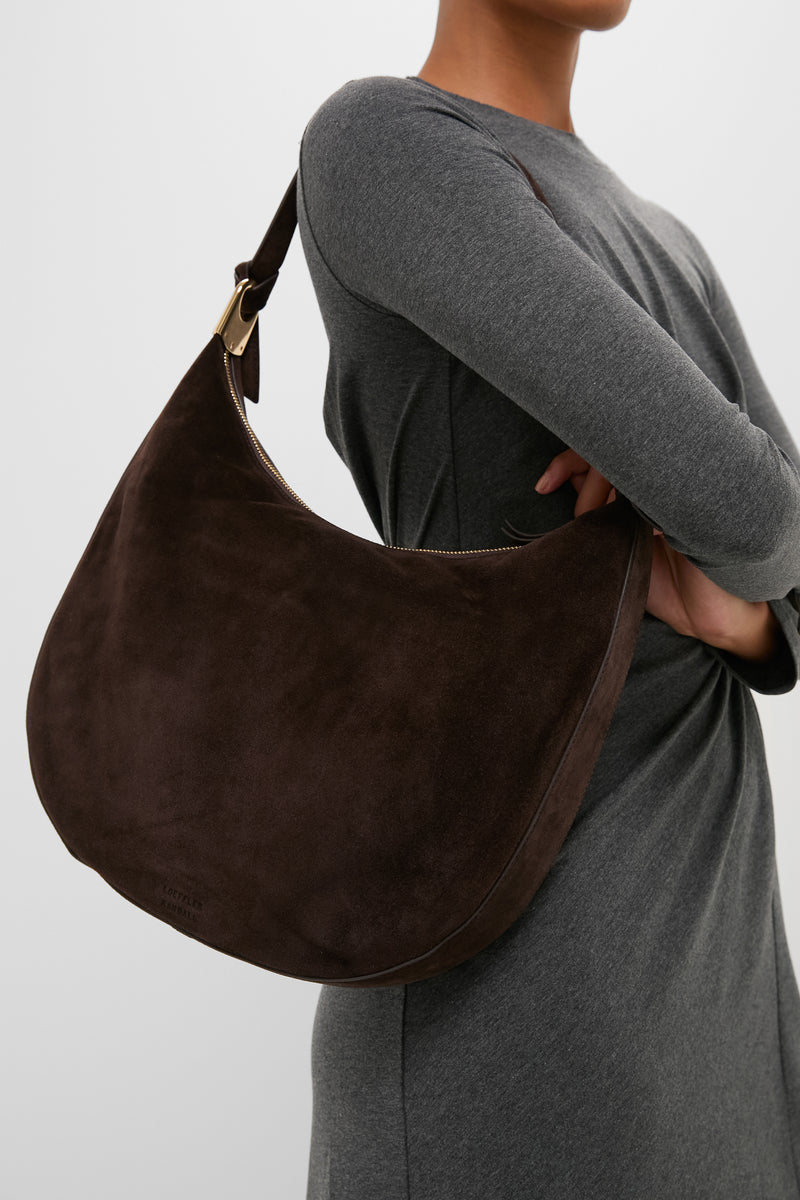 Model wearing a classic long-sleeve grey dress, showcasing the high-end Tmoro Suede with Gold Morgan Shoulder Bag. Effortlessly combines fun elegance with practical design.