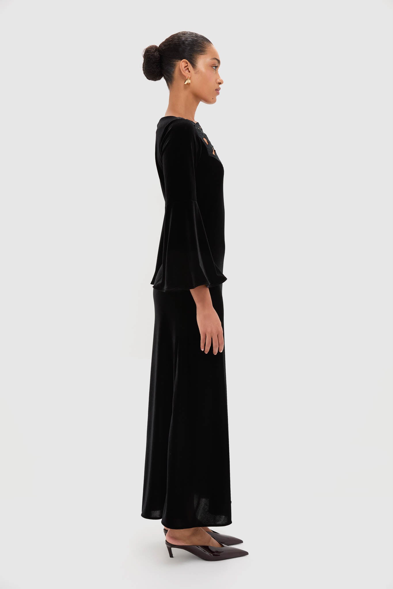 Model in Accademia Black Velvet Bell Sleeve Catherine Maxi Dress with lace yoke and flared sleeves, styled with sculptural earrings and slingback pumps for an effortless, high-end look.