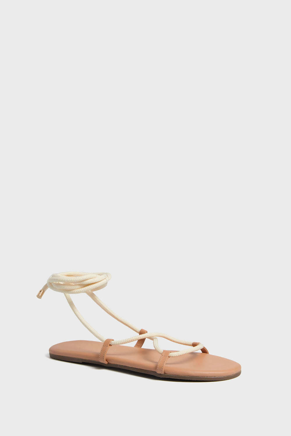 The TKEES flat lace-up sandal features a tan sole and cream rope straps, complete with a stylish wrap-around ankle tie.