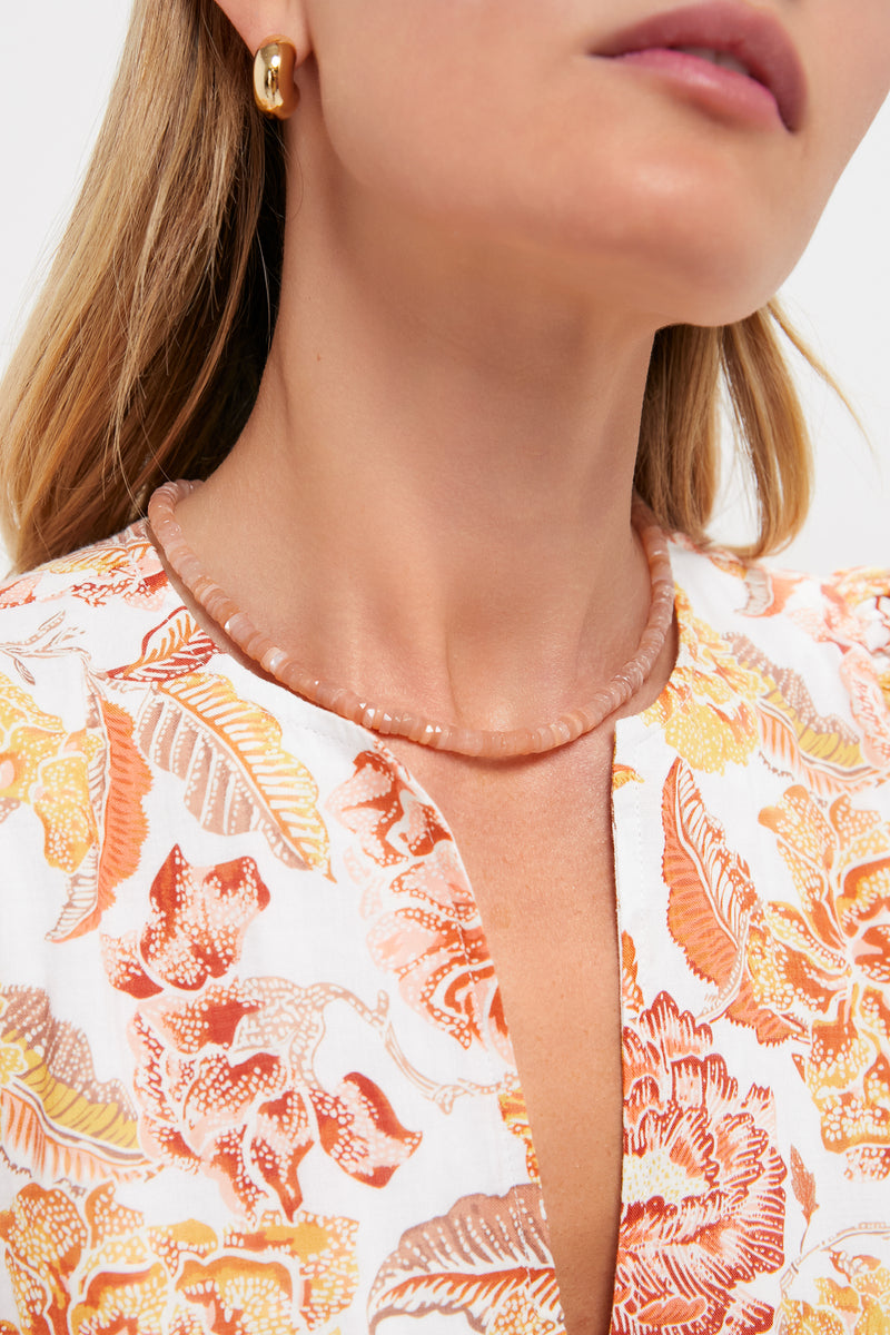 Woman wearing the Peach Moonstone Candy Necklace; classic, faceted peach beads on her neck, paired with a chunky gold hoop earring for an effortless, high-end style.