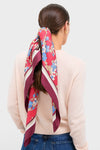 Scarlet Sakura Medium Silk Scarf in a classic low ponytail style, showcasing its effortless, high-end floral design against a light-pink sweater for a fun, chic look.