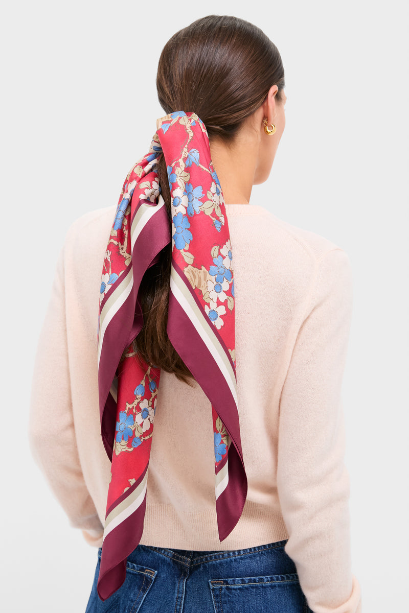Scarlet Sakura Medium Silk Scarf in a classic low ponytail style, showcasing its effortless, high-end floral design against a light-pink sweater for a fun, chic look.