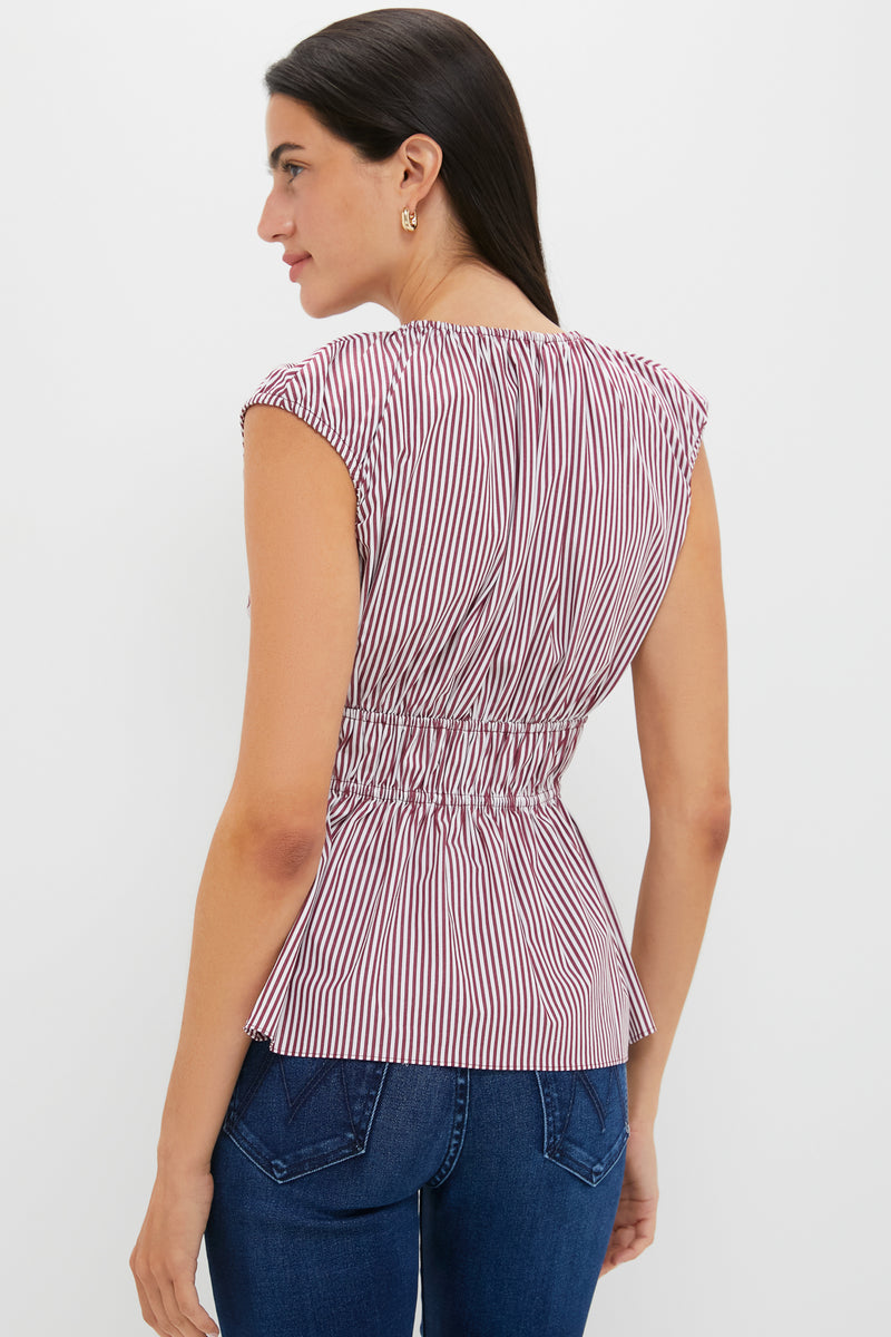Woman wearing the classic Burgundy Maia Stripe Hedda Top with V-neckline, gathered peplum hem, and tie detail, paired effortlessly with jeans for a high-end, fun look.