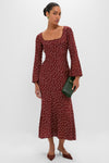 Woman in a burgundy Burnt Umber Narah Maxi Dress with polka dots, holding a dark-green clutch, embodying classic, effortless style with fun, high-end details like flared sleeves.