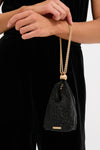 Person holding the Black Rue Wristlet, a classic, high-end evening bag with a glittering mesh, gold clasp, and chain strap, embodying effortless and fun sophistication.