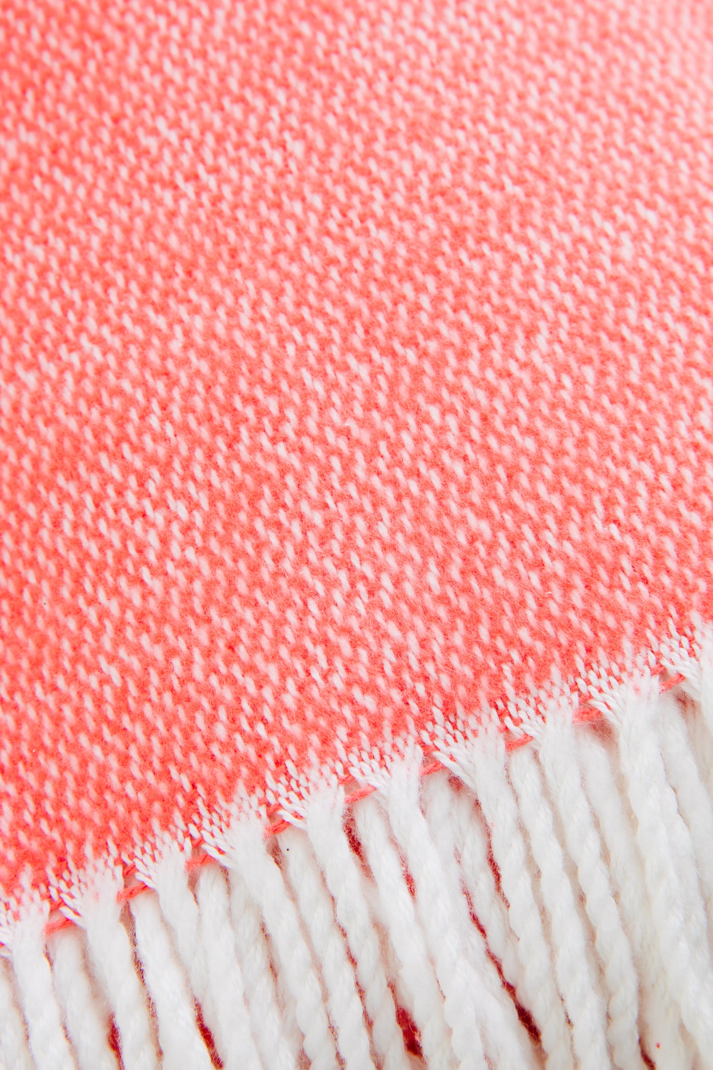 Coral Pezzo Throw with classic white fringe, effortlessly combining high-end craftsmanship and fun style in soft brushed cotton, perfect for any lounging space.