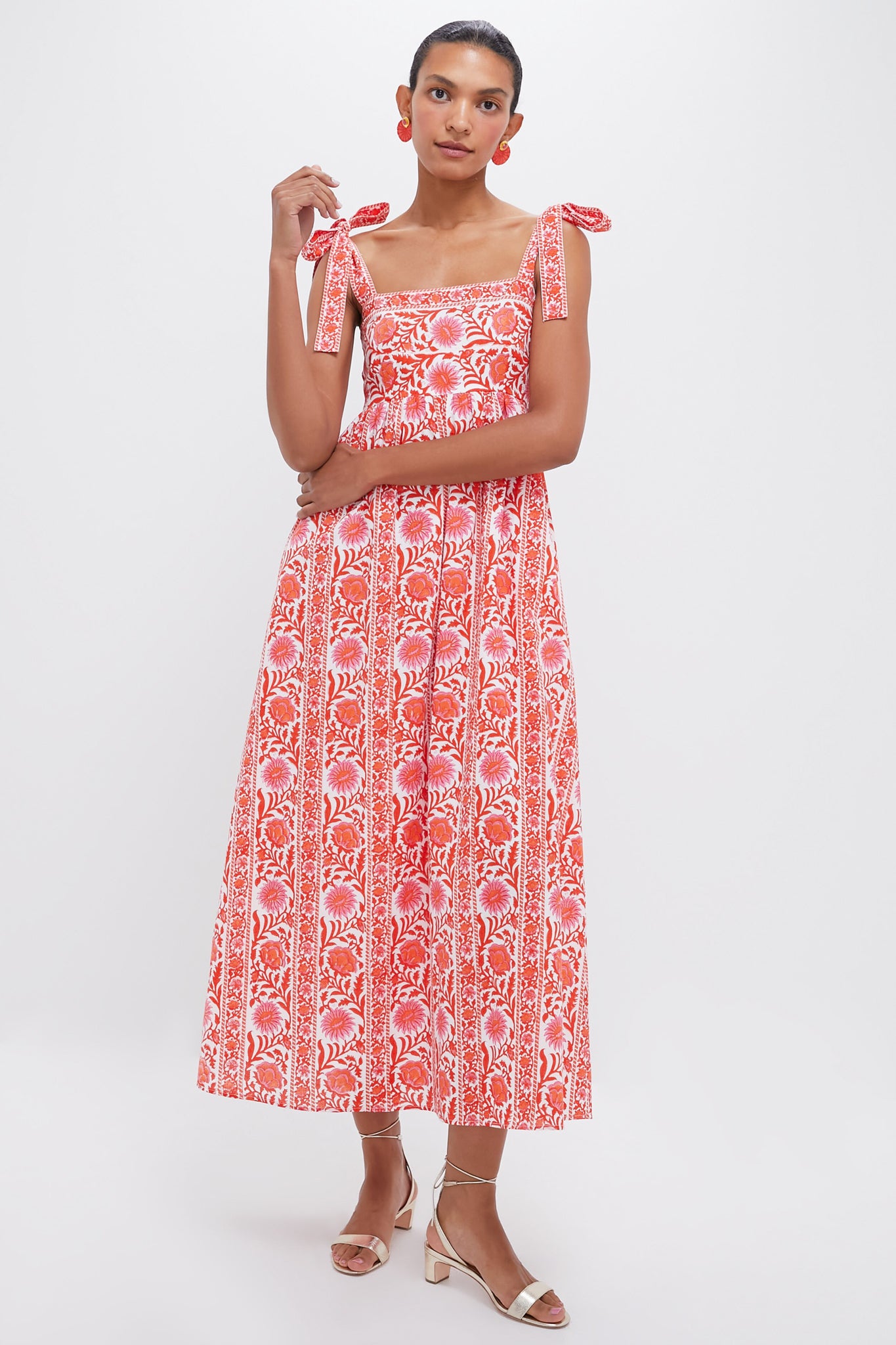 A woman wears a Pink City Prints red and white block-printed maxi dress with tie straps, paired with matching earrings and open-toed heels.