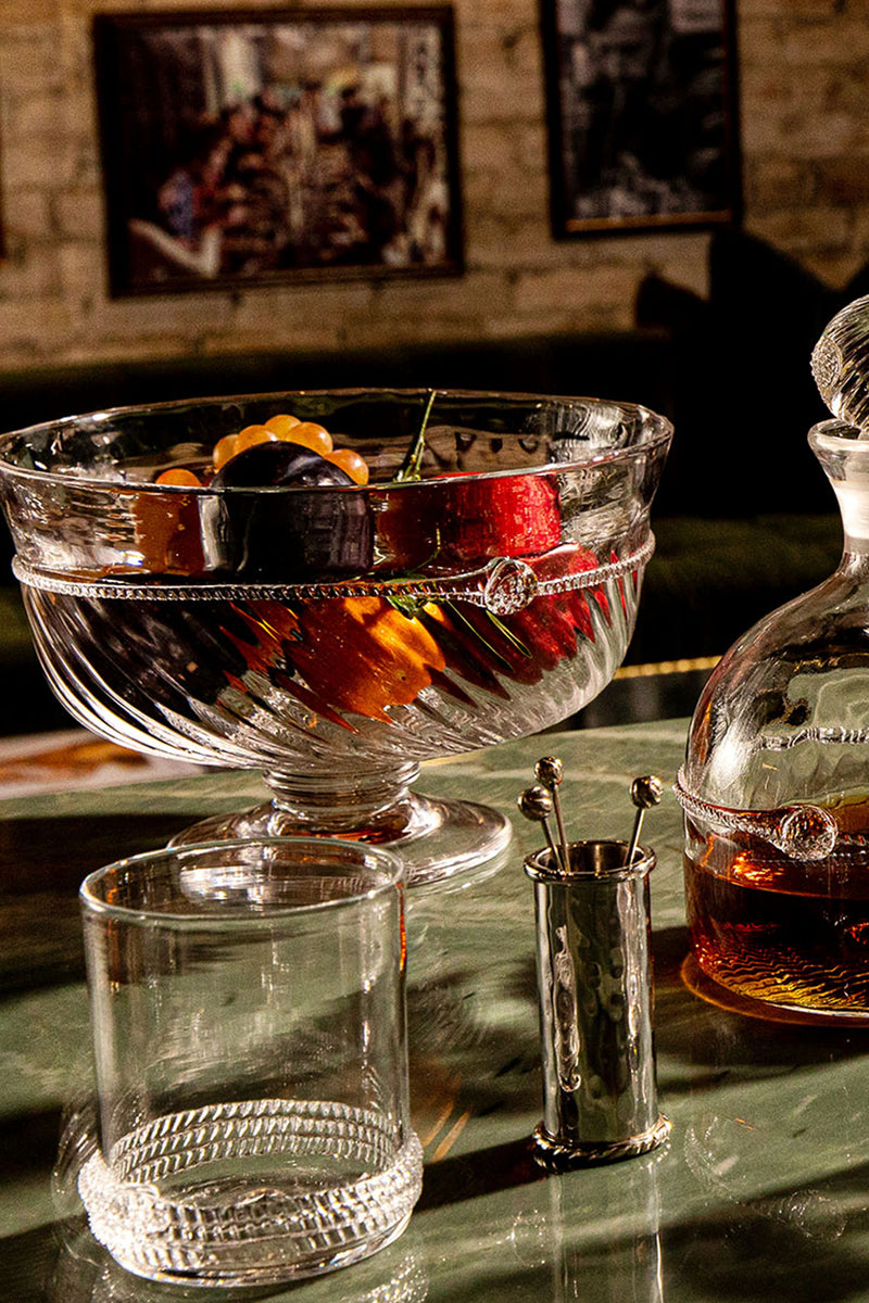 Graham 10 Footed Bowl elegantly displays assorted fruit, paired with a classic decanter and tumbler, embodying an effortless, high-end tabletop arrangement.