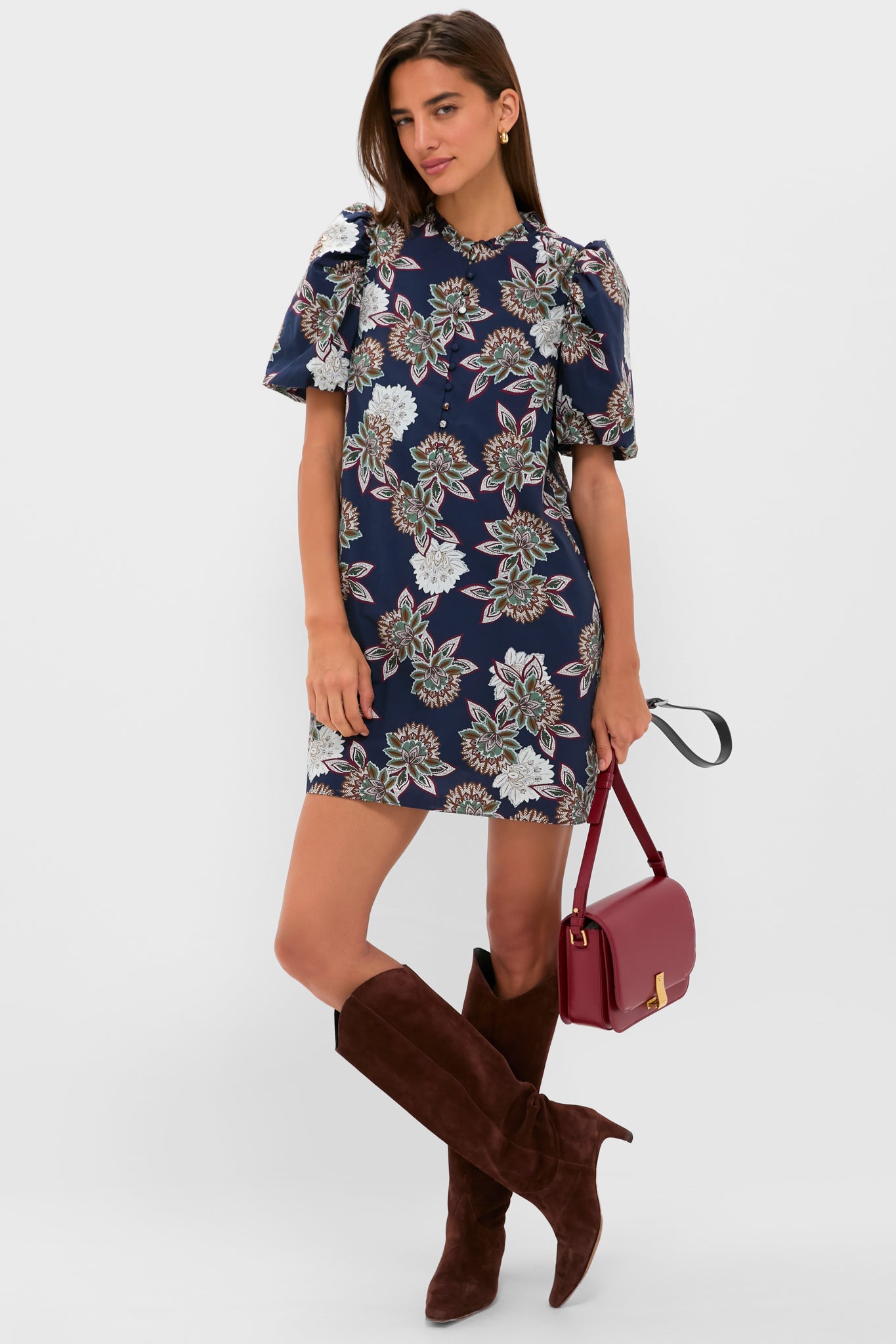 Model wearing the Navy Floral Mimi Mini Dress with classic puff sleeves and ruffle collar, paired effortlessly with dark brown knee-high boots and a burgundy crossbody bag.