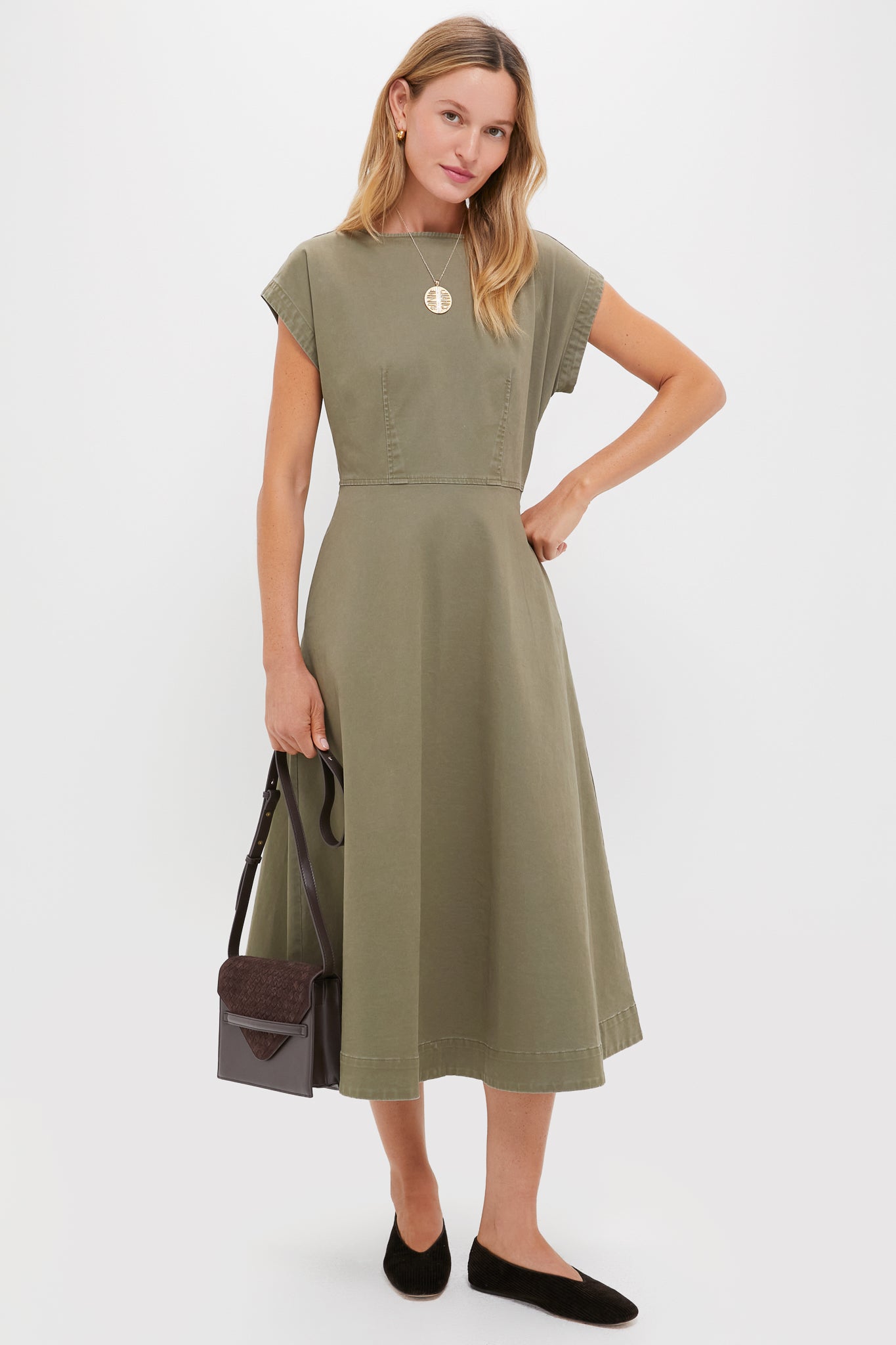 Model in olive midi dress wearing Gold Jumbo Bonne Chance Coin Necklace, exuding effortless elegance. Accessorized with classic flats and a chic shoulder bag for a high-end, fun look.