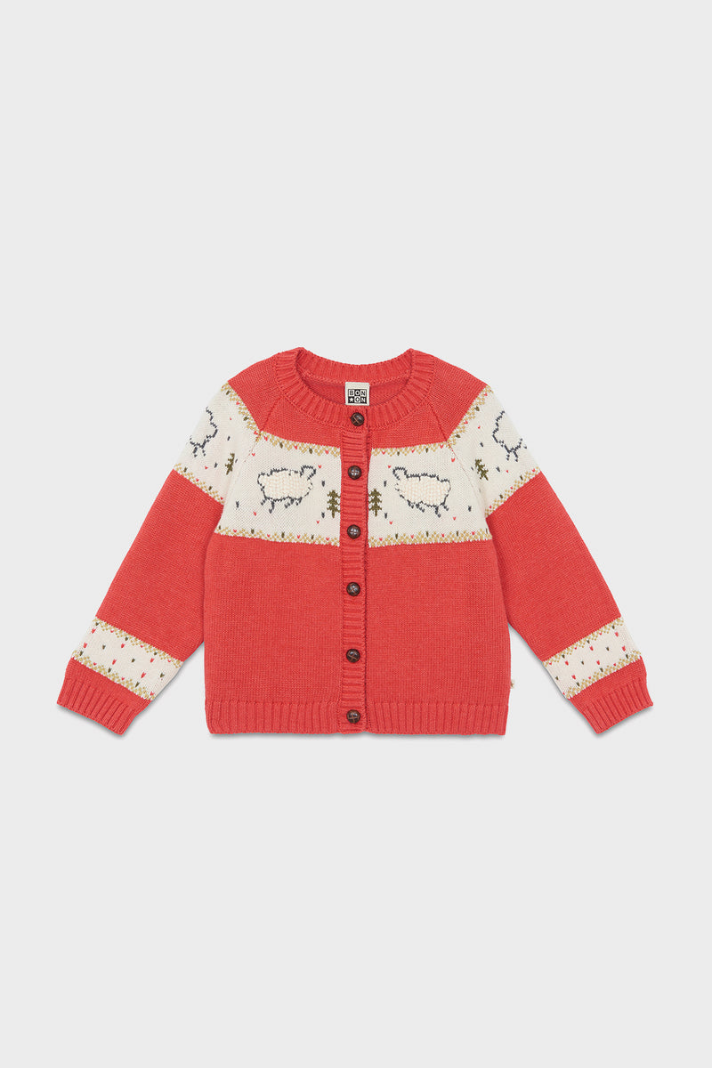 A cozy red knit sweater for children by Bonton, featuring a sheep pattern, cream panels, long sleeves, and a button-up front—perfect for winter and inspired by French kids' fashion.