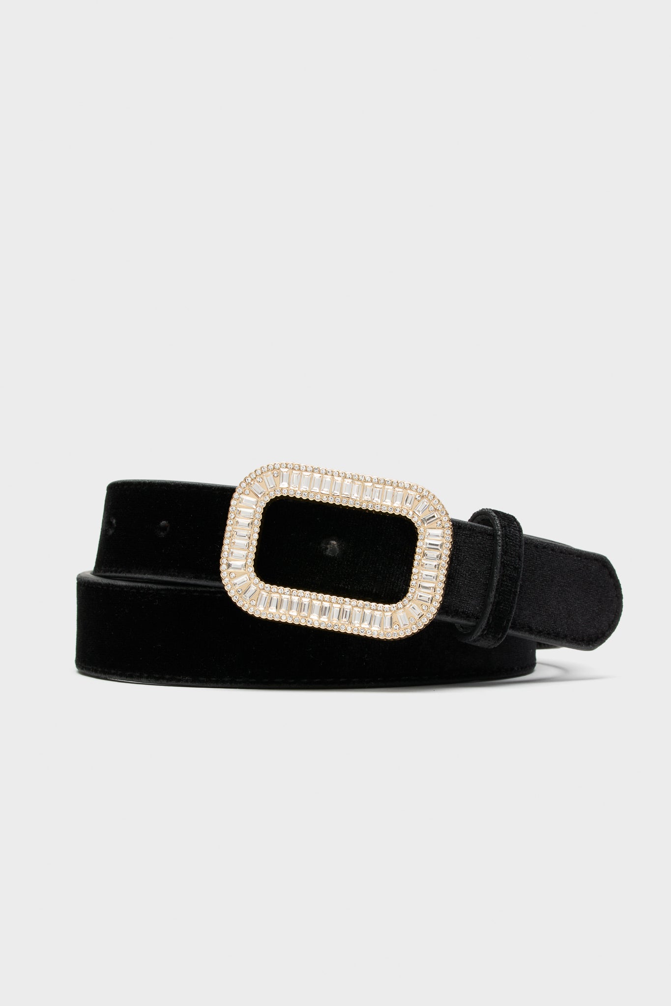 Tuckernuck Accessories presents a black velvet waist belt with an adjustable rectangular gold-tone buckle embellished with clear rhinestones.
