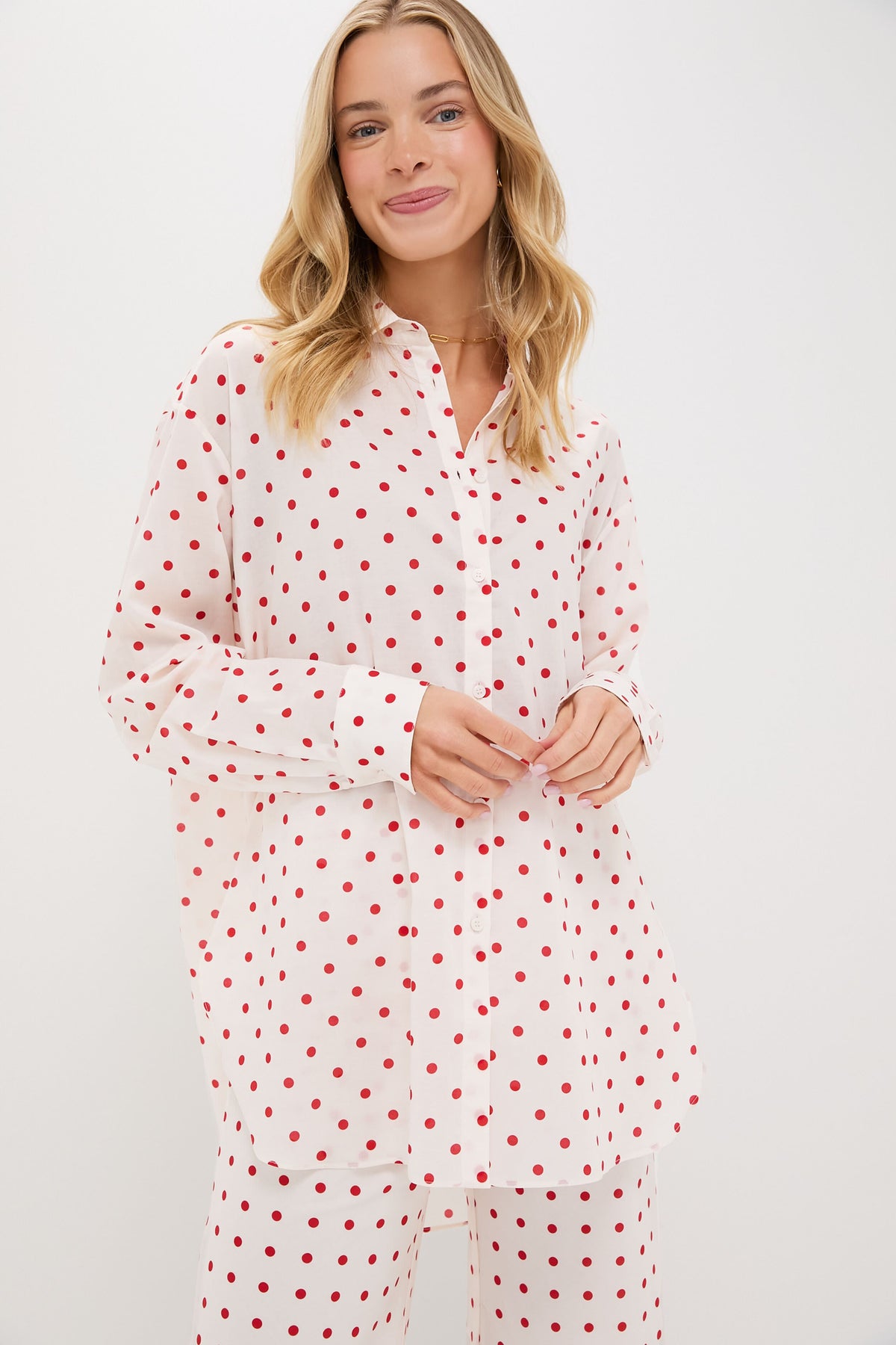 A woman wears a white, oversized fit POSSE shirt and matching pants, both featuring a red polka dot pattern.