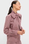 Model wearing Mauve Stripe Brianna Bow Blouse with an oversized bow, blouson sleeves, and chunky gold hoops, showcasing a classic, effortless high-end style.