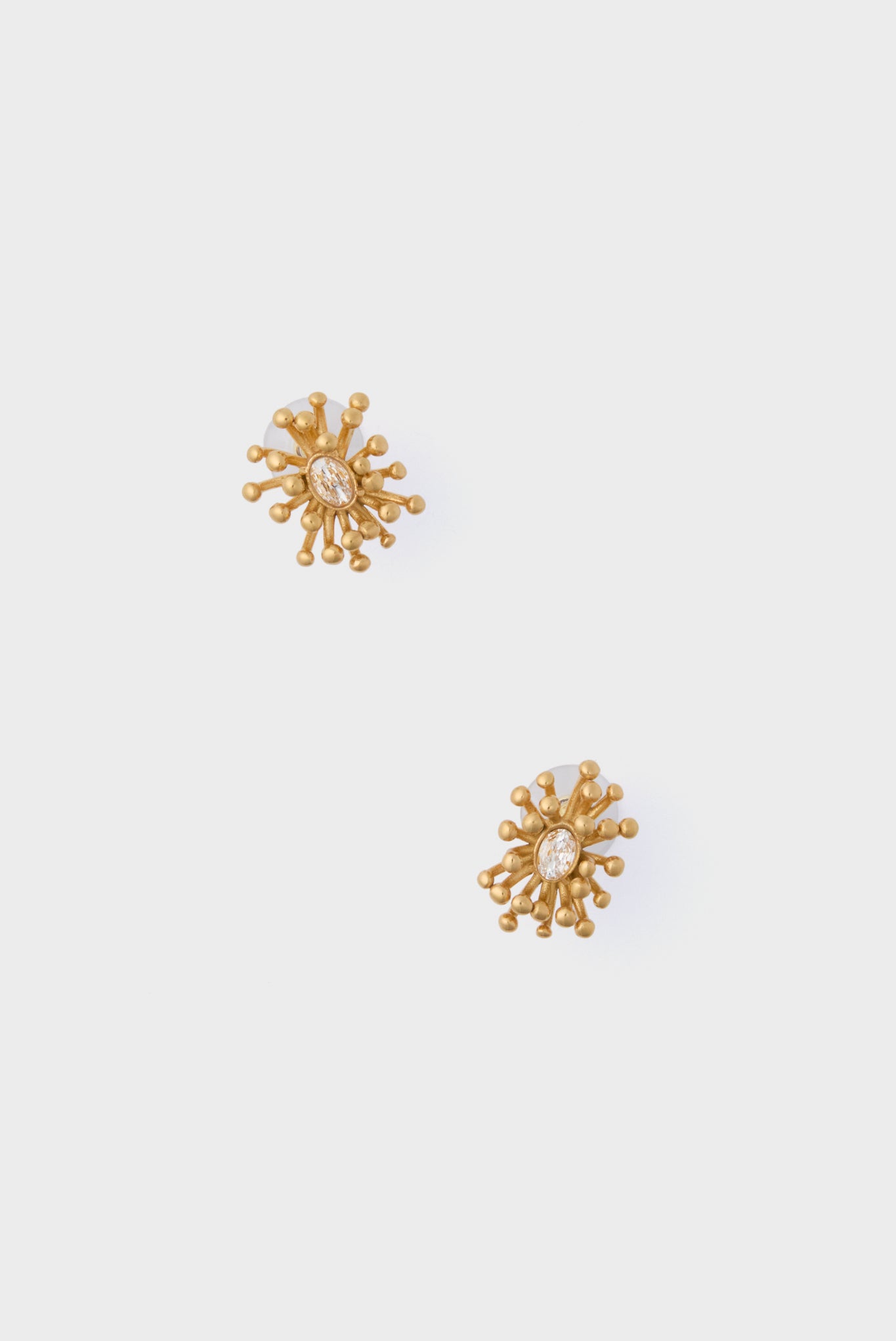 Explore Petit Moments' gold stud earrings, highlighted by a bold sunburst motif and an eye-catching oval centerpiece.