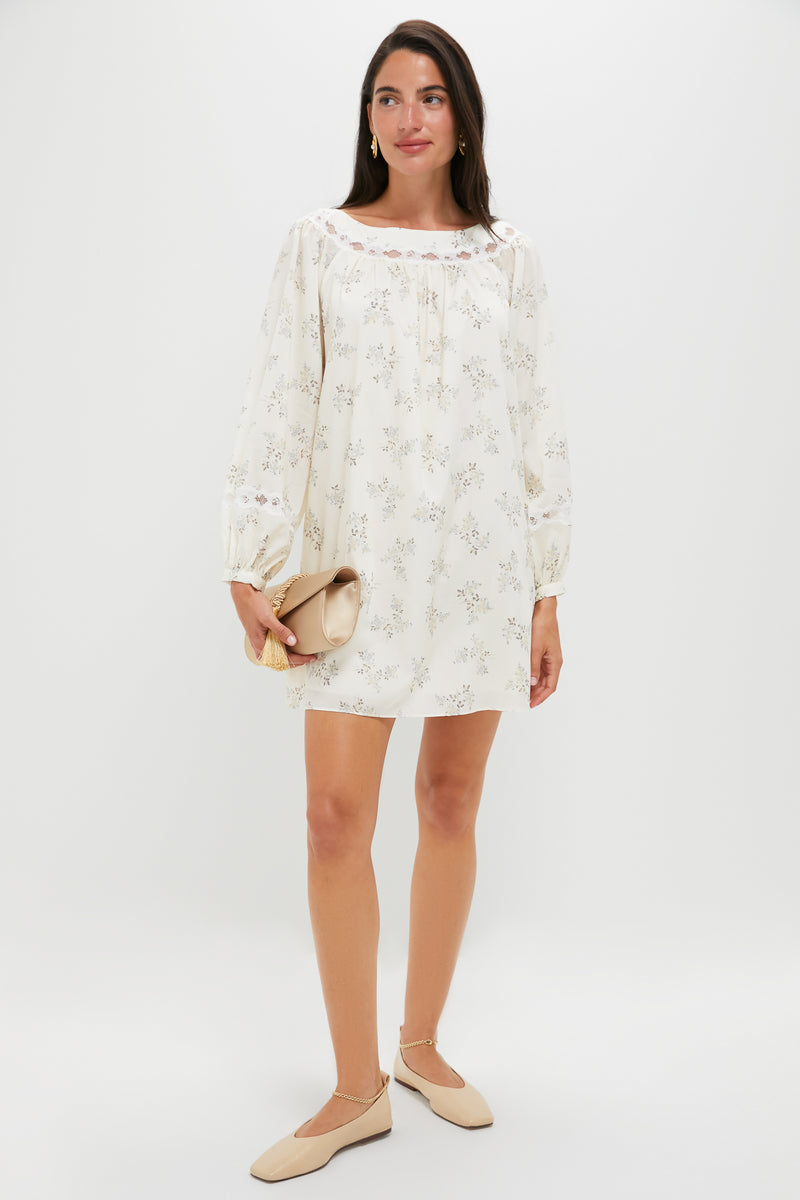 Model in floral mini dress holds a tan clutch, showcasing classic Gold Trumbull Earrings. Effortlessly high-end and fun, perfect for any occasion.