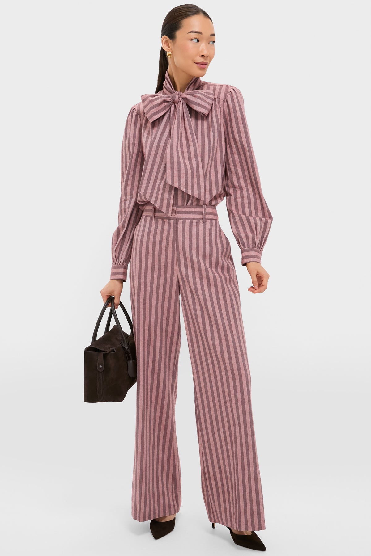 Woman models classic, high-end Mauve Stripe Wyatt Pants with a banded waist and wide-leg silhouette, paired with a matching bow blouse for an effortless, fun look.
