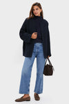 Person wearing the classic Navy Boucle Barrett Coat with a relaxed fit over a turtleneck, paired with jeans and loafers, holding a suede handbag for an effortless, high-end look.
