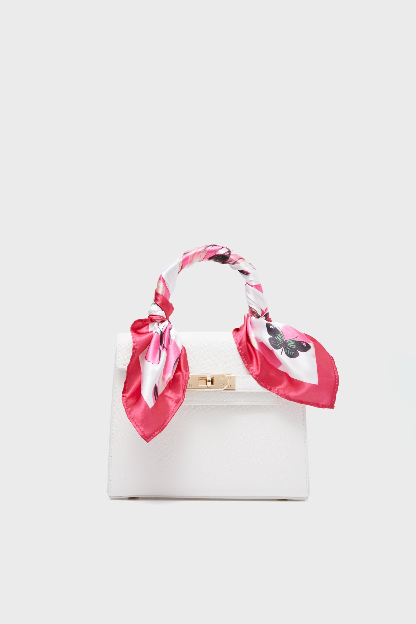The Urban Expressions white premium vegan leather handbag features a gold clasp and a pink patterned scarf on the handle—perfect for stylish, animal-friendly fashion.