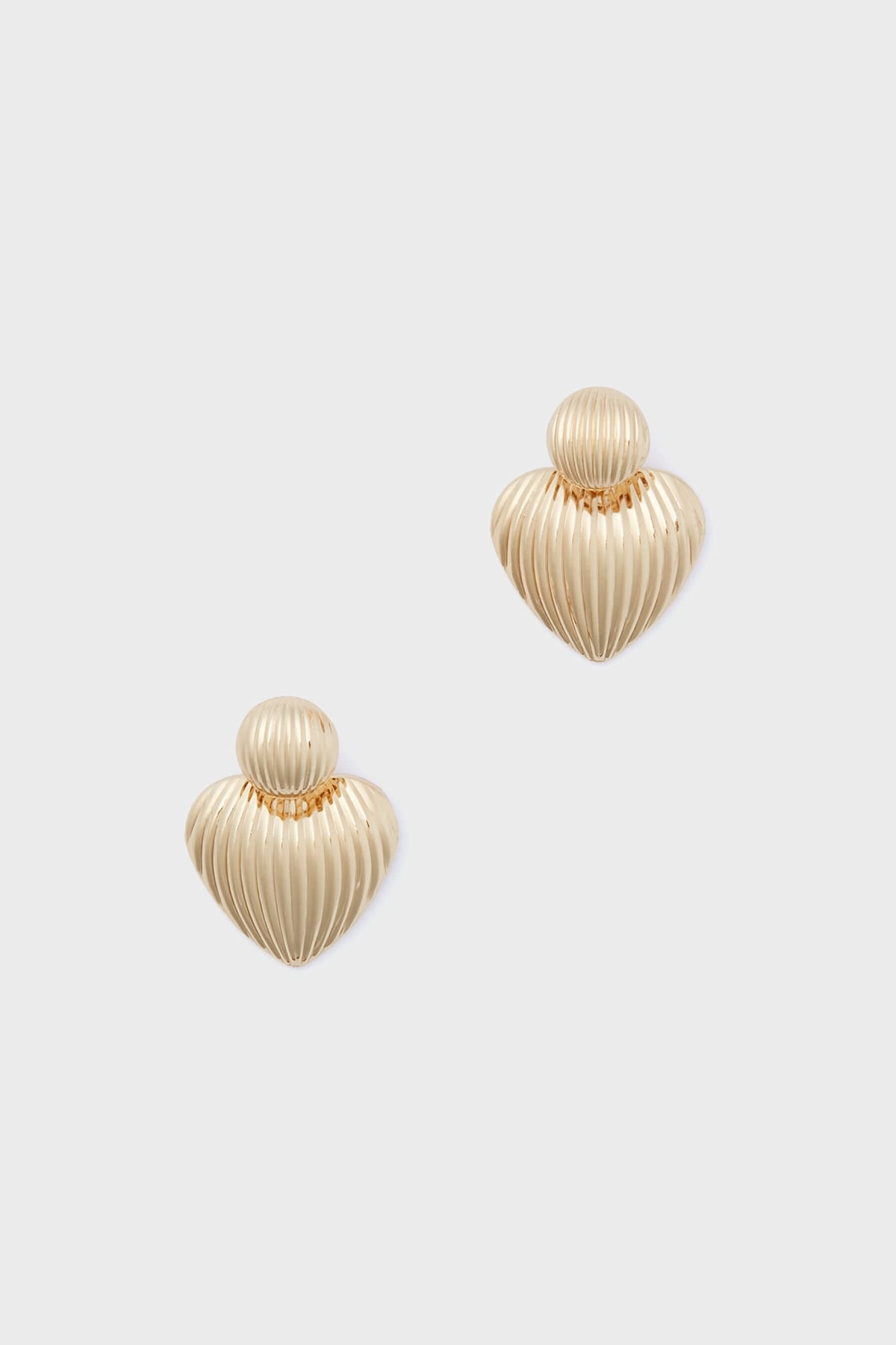 A pair of Petit Moments Gold Felix Earrings featuring gold-tone ribbed, heart-shaped studs—perfect for adding a touch of Los Angeles jewelry style to any outfit.