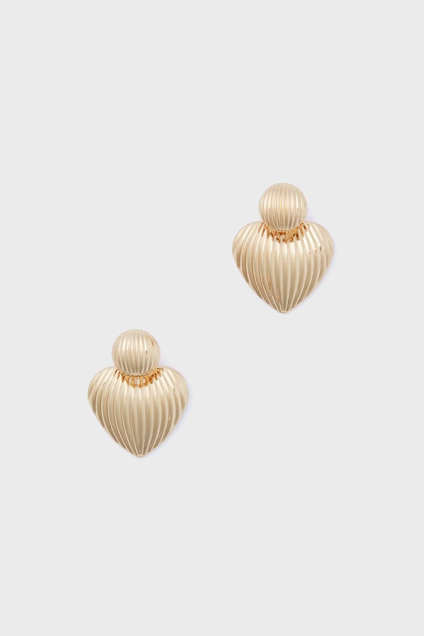 A pair of Petit Moments Gold Felix Earrings featuring gold-tone ribbed, heart-shaped studs—perfect for adding a touch of Los Angeles jewelry style to any outfit.