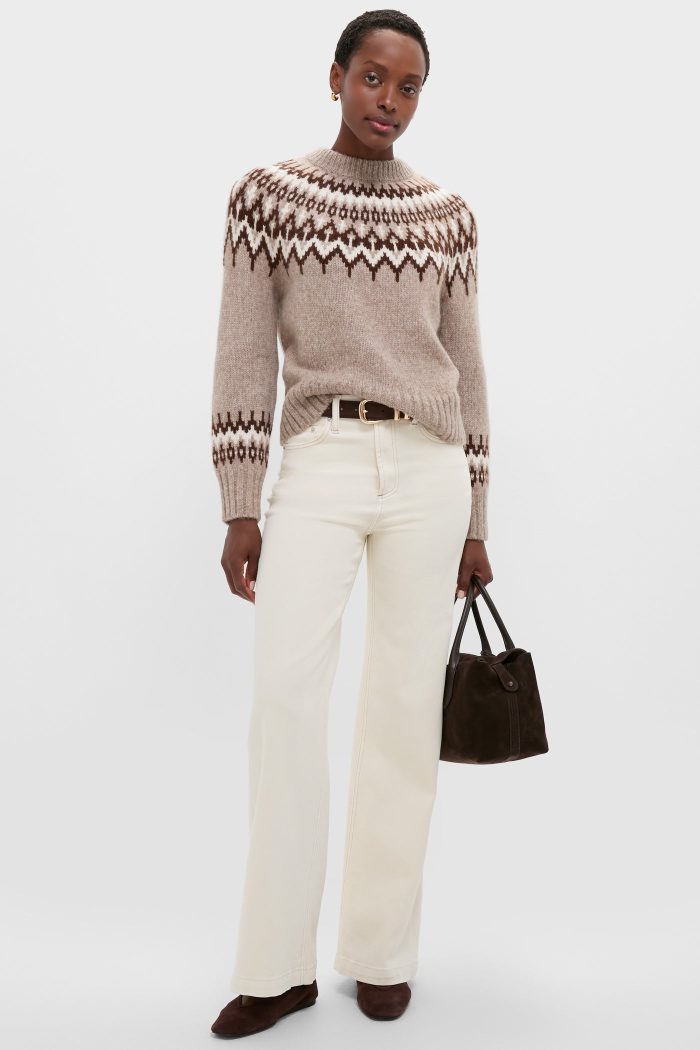 Woman models the classic Taupe Fairisle Thatcher Crewneck with effortless style, paired with flared jeans, dark suede boots, and a chic handbag.