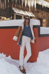 Young woman in a classic Navy Striped Jansen V-Neck Polo Sweater, styled effortlessly with off-white jeans and tan shearling jacket, exuding high-end winter fashion.