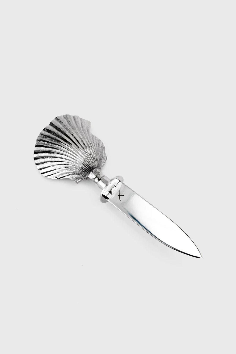 A Shelton Metal hand-carved oyster knife with a stainless steel blade and a scallop shell-shaped handle is displayed on a plain surface.