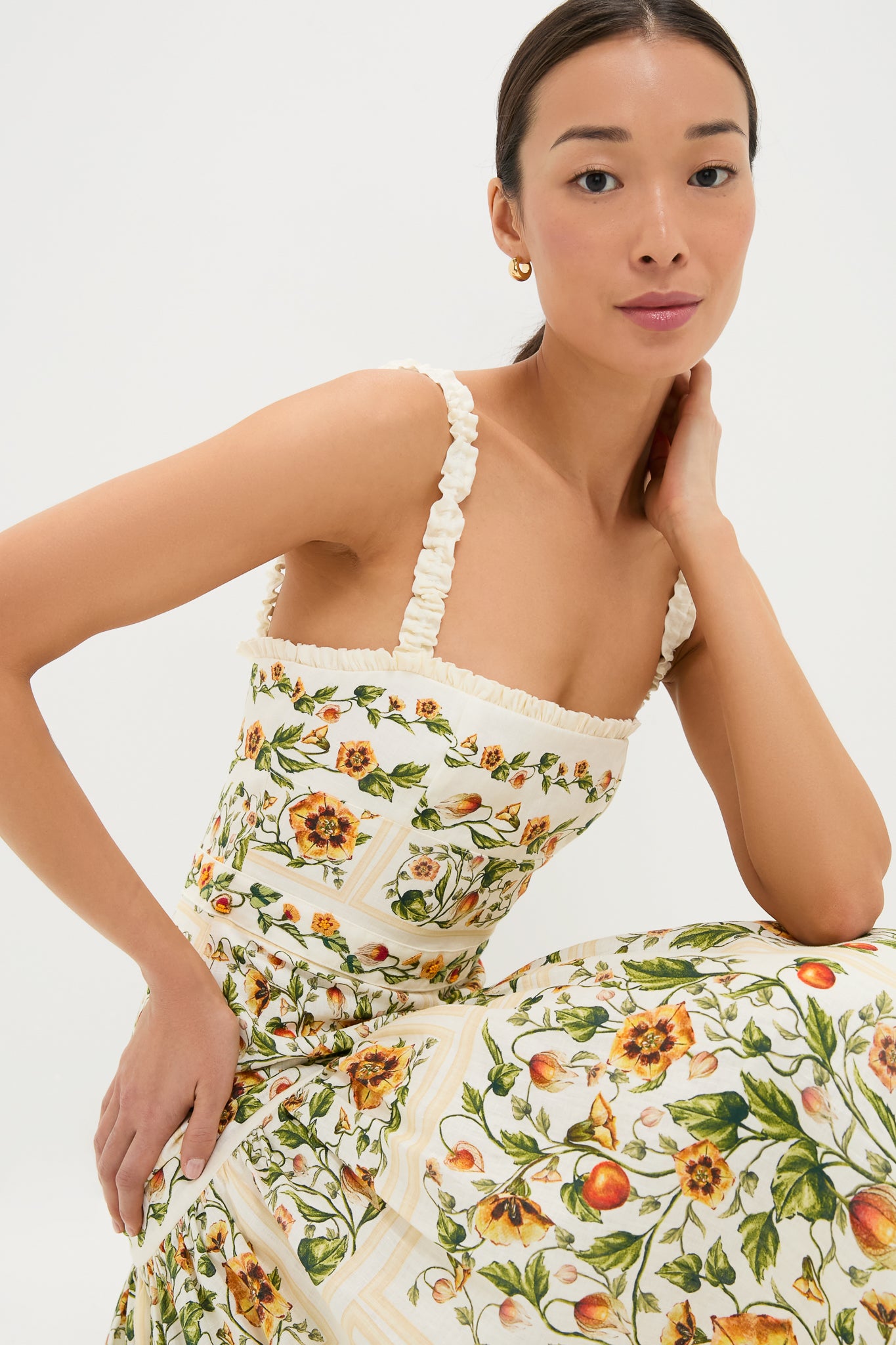 Young woman models the Uchuva Nispero Midi Dress, a classic, high-end piece with an effortless botanical pattern, ruched straps, and a fitted bodice, embodying fun sophistication.