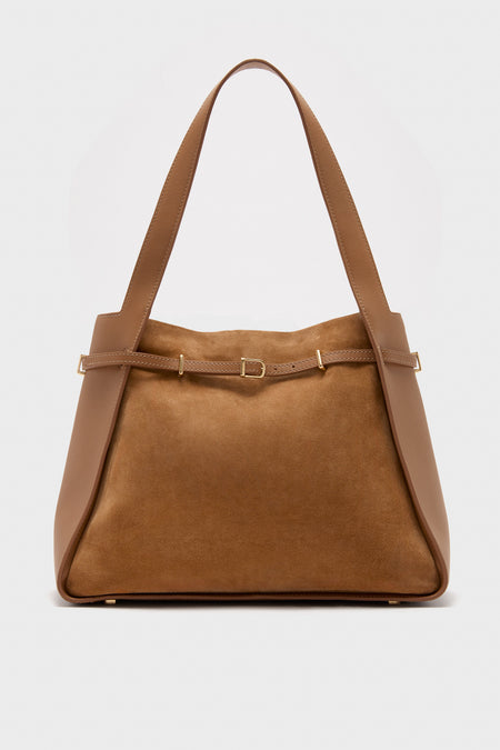 The SIMKHAI tote is crafted from brown leather and calf suede, featuring wide shoulder straps and a decorative belt detail across the front.