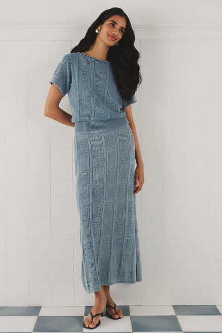 Woman in a matching crochet skirt set in blue. 