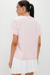 Woman in a classic, effortless Pink Short Sleeve Performance Jersey Ryan Boyfriend Tee, showcasing a fun, high-end look with a white pleated skirt.