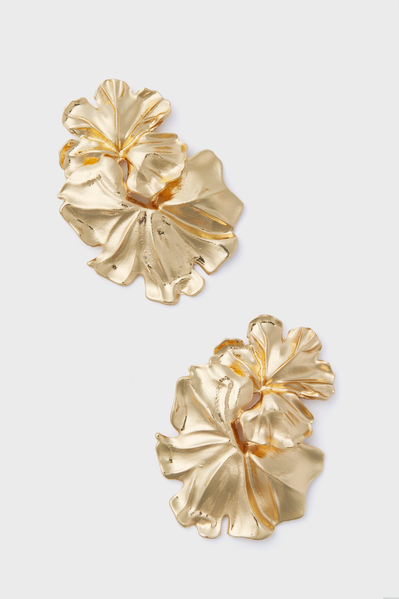 A pair of Petit Moments Gold Noveldo Earrings featuring a statement flower design with textured, gold-toned abstract leaves.