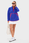 Person wearing a classic Blue and Red Fleece Cady Quarter Zip over a white skirt, styled with sunglasses and a tote bag for an effortless, fun, high-end look.