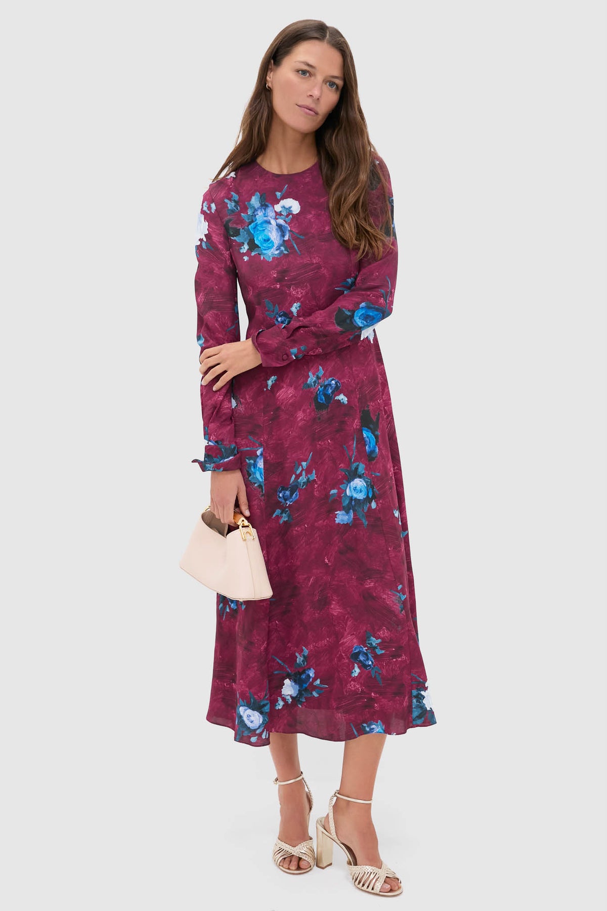 Woman models the classic Abstract Rose Milberry Red Long Sleeve Midi Dress, effortlessly styled with a cream handbag and neutral strappy sandals, embodying fun and high-end elegance.