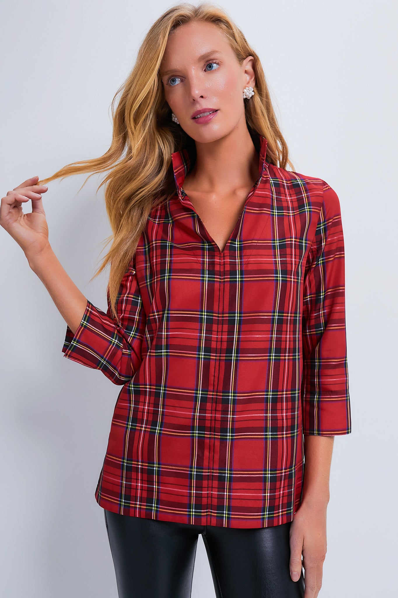 A woman wears a Tuckernuck red Royal Stewart Tartan Margot Top with a split collar and black pants.
