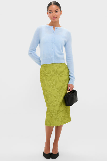 Model wearing the classic Ice Blue Cashmere Riley Cardigan, styled effortlessly with a textured green pencil skirt, black pumps, and a high-end black handbag.