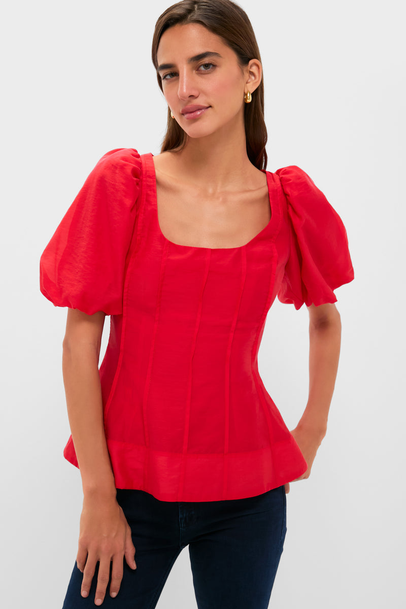 A woman stands confidently in a Hyacinth House ruby red, puff sleeve blouse with a square neckline and dark jeans.