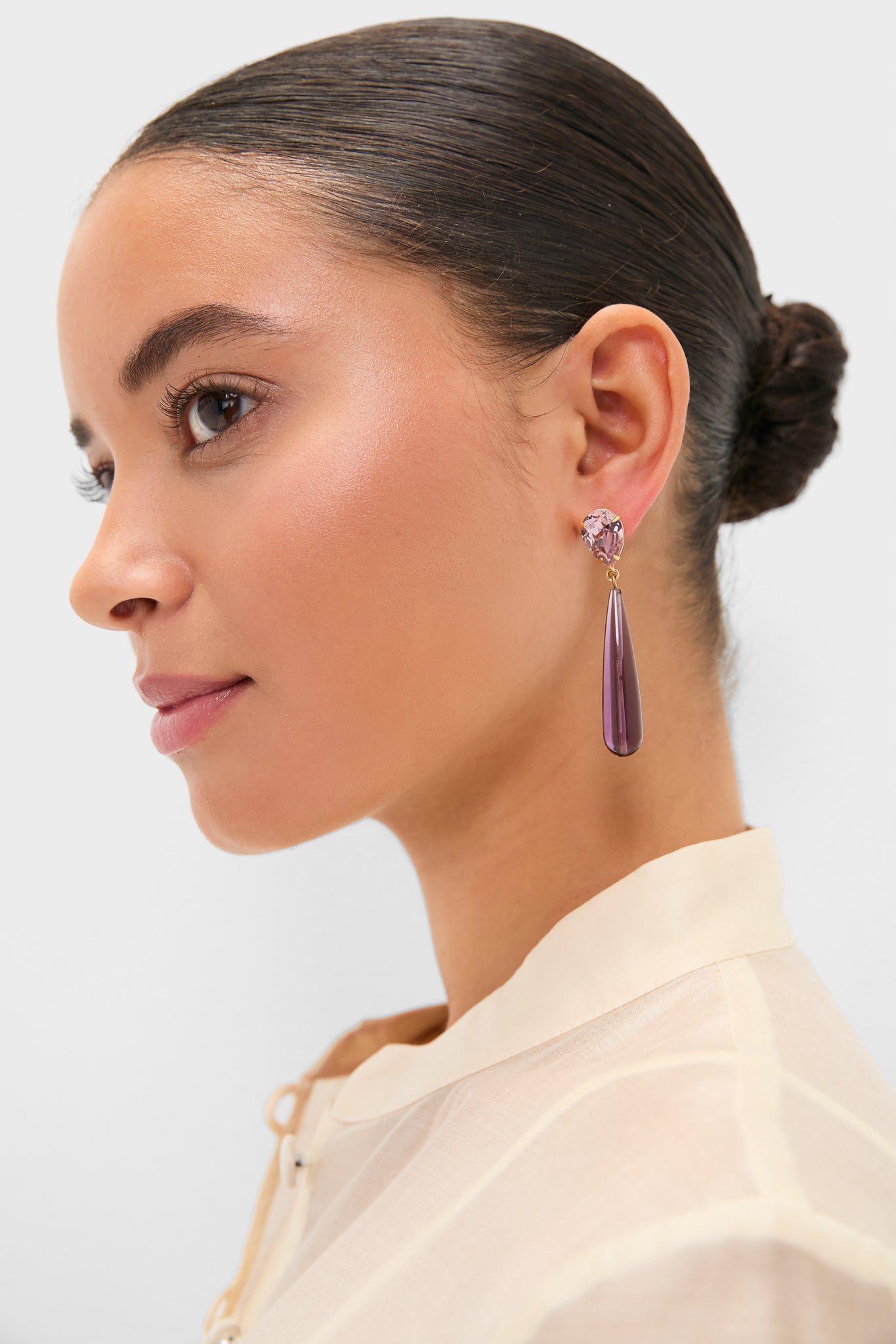 Young woman wearing Amethyst Caroline Earrings featuring a classic, effortless design with a faceted pink stud and smooth purple teardrop pendant, embodying Tuckernuck's high-end, fun style.