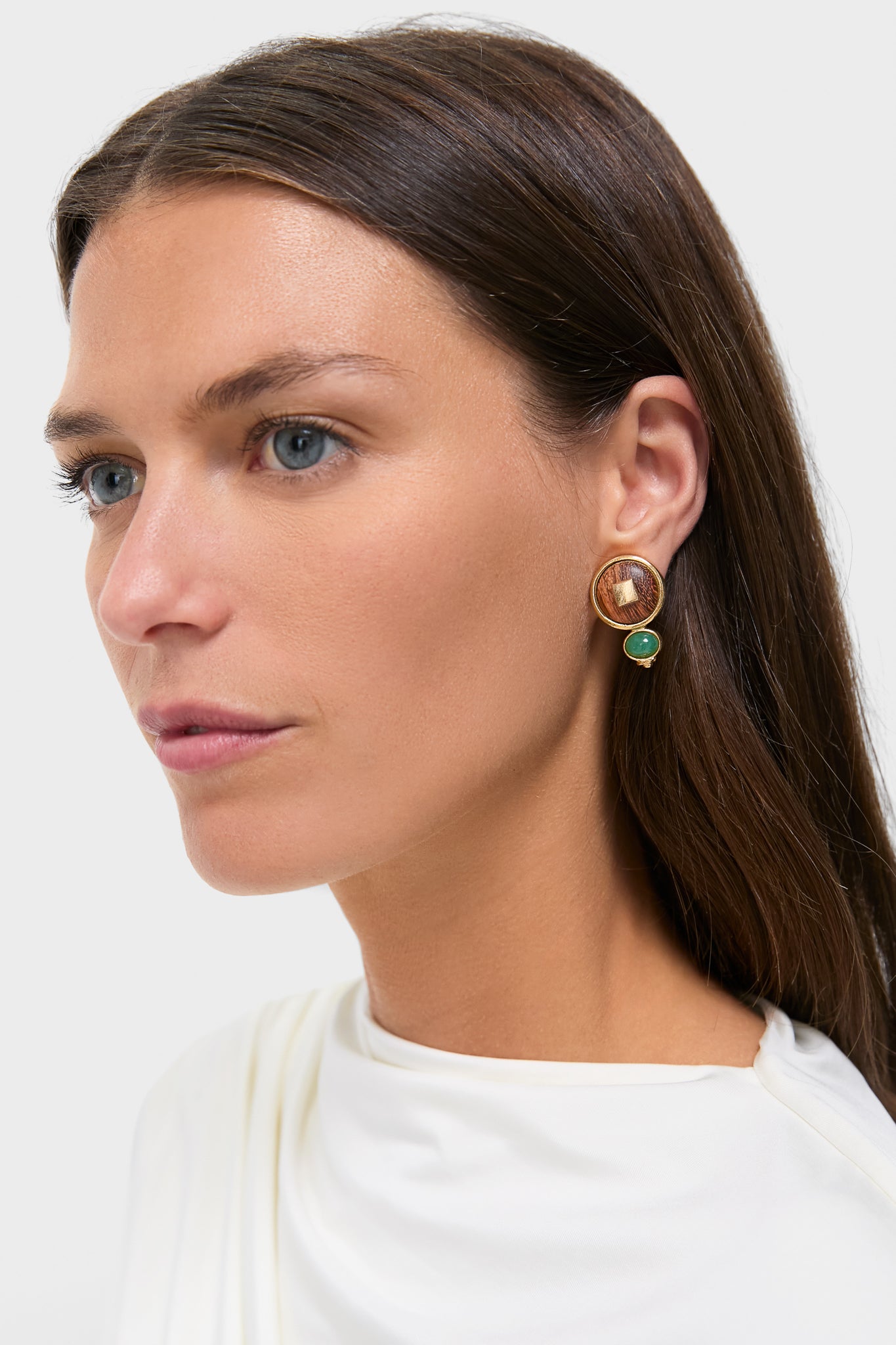 Woman wearing Oak and Green Earrings: classic gold-tone studs with wood-textured inlay and dangle green stone, offering an effortless, high-end touch to any outfit.