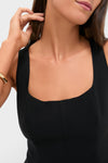 Woman wearing the Black Sleeveless Decker Peplum Top with a square neckline, paired with a chunky gold bracelet, embodying an effortless, high-end, and fun classic style.