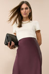 Woman in an ivory short sleeved top and satin skirt. 