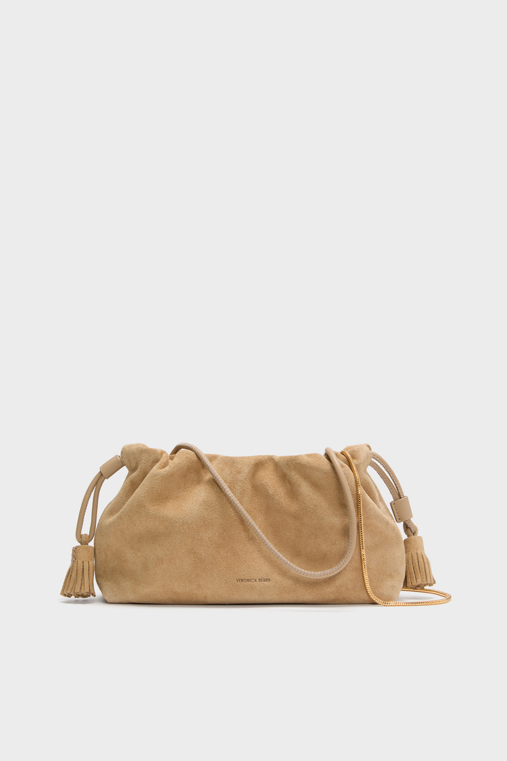 The Veronica Beard Italian suede bag features a tan color, drawstring closure, tassel accents on both sides, and a thin strap—making this small crossbody perfect for effortless style.