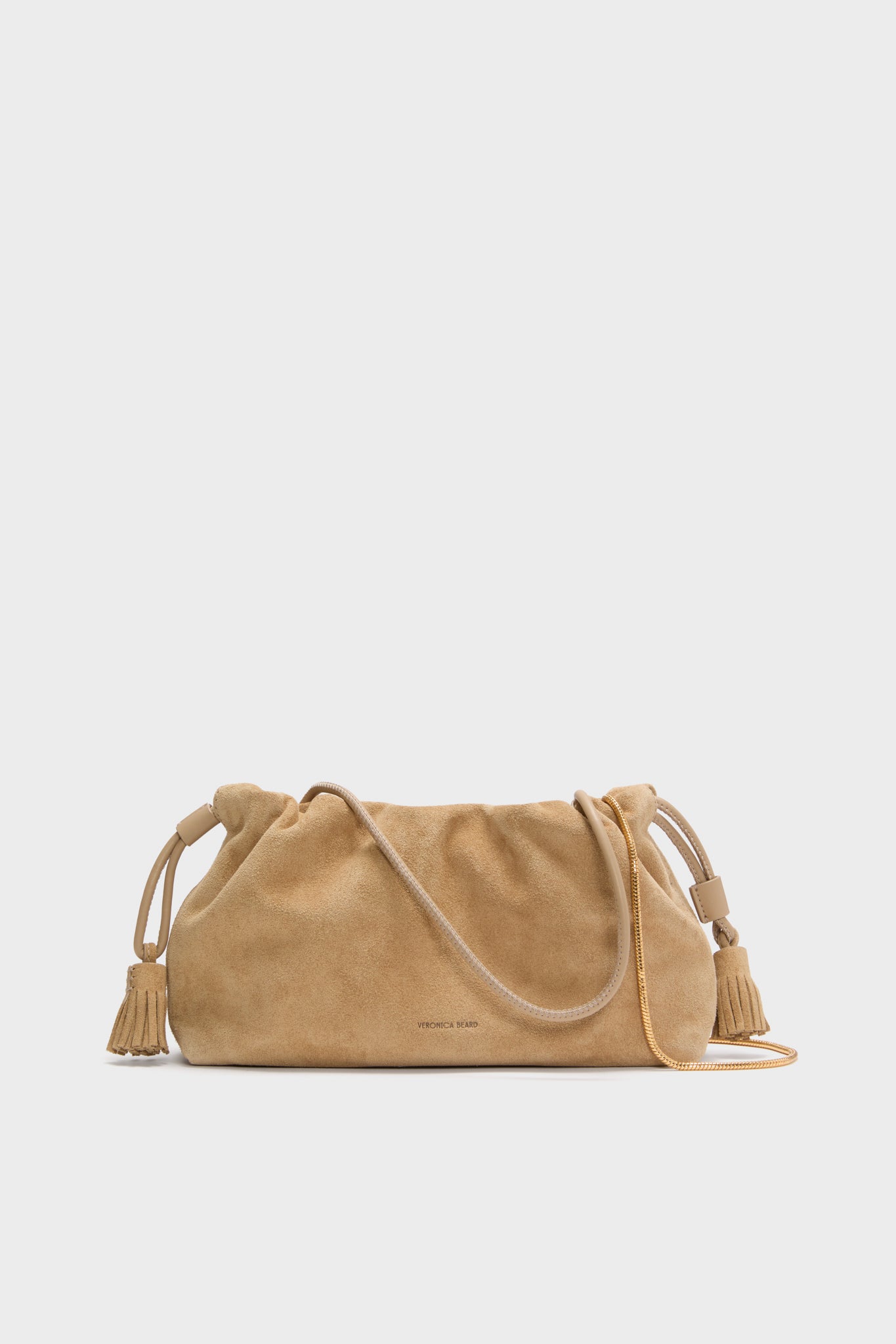 The Veronica Beard Italian suede bag features a tan color, drawstring closure, tassel accents on both sides, and a thin strap—making this small crossbody perfect for effortless style.