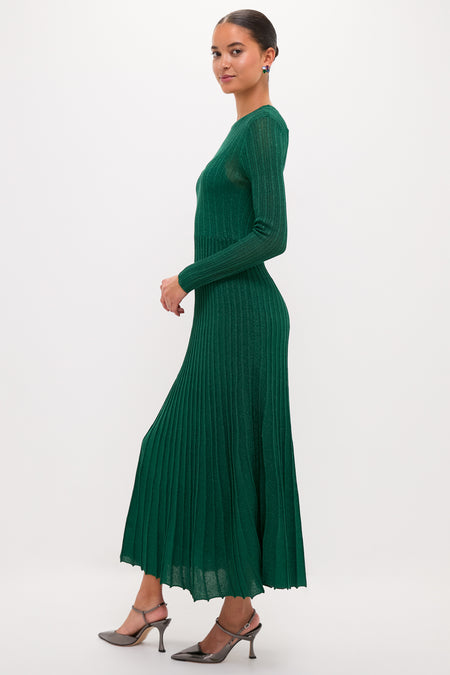 Model in profile wearing a classic, high-end Green Shimmer Knit Cammie Maxi Dress with pleated skirt and slingback heels, exuding effortless elegance and fun sophistication.