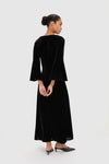 Woman in Accademia Black Velvet Bell Sleeve Catherine Maxi Dress, showcasing classic elegance with flared sleeves and lace yoke, styled with effortless sophistication.