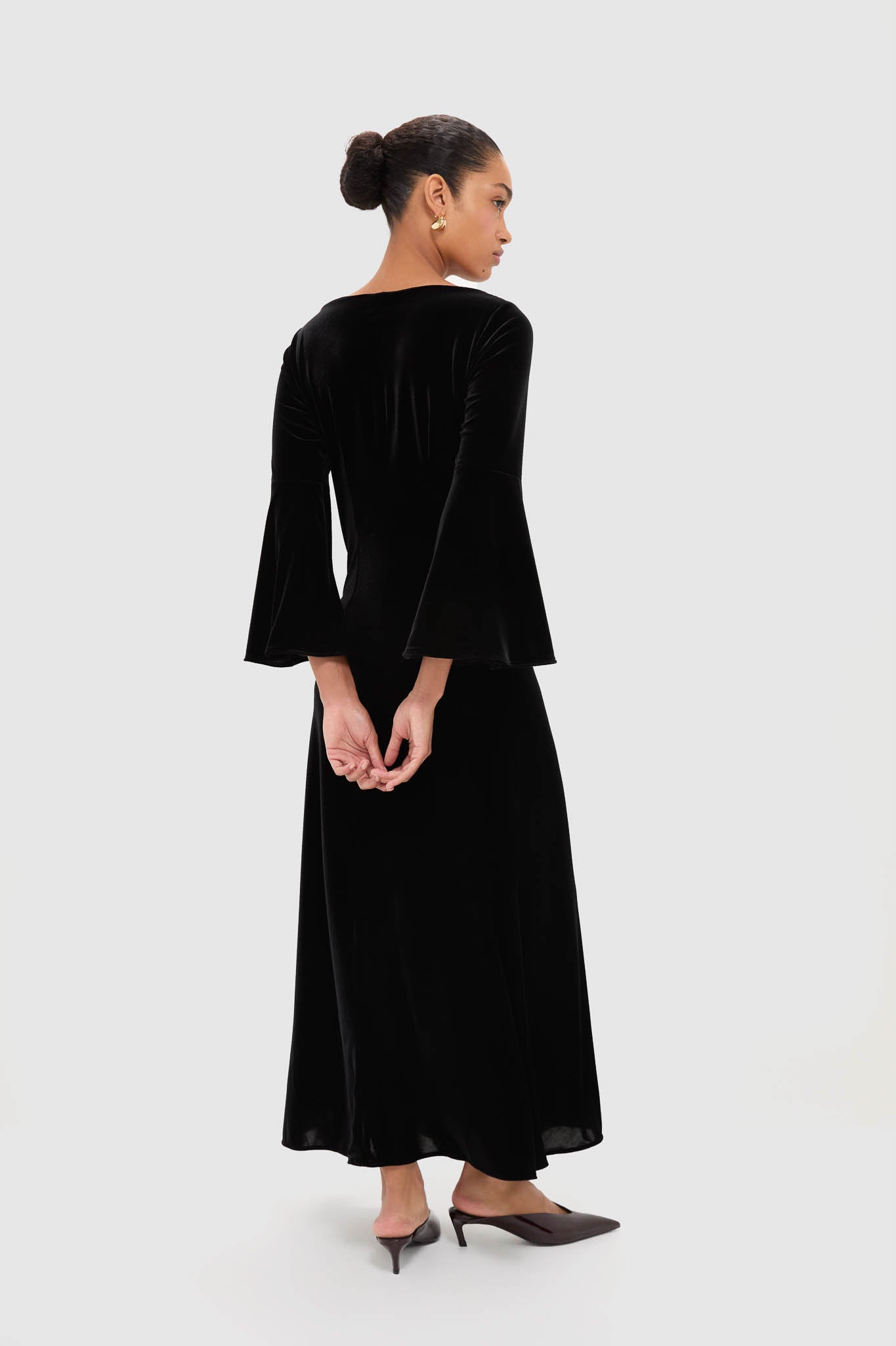 Woman in Accademia Black Velvet Bell Sleeve Catherine Maxi Dress, showcasing classic elegance with flared sleeves and lace yoke, styled with effortless sophistication.