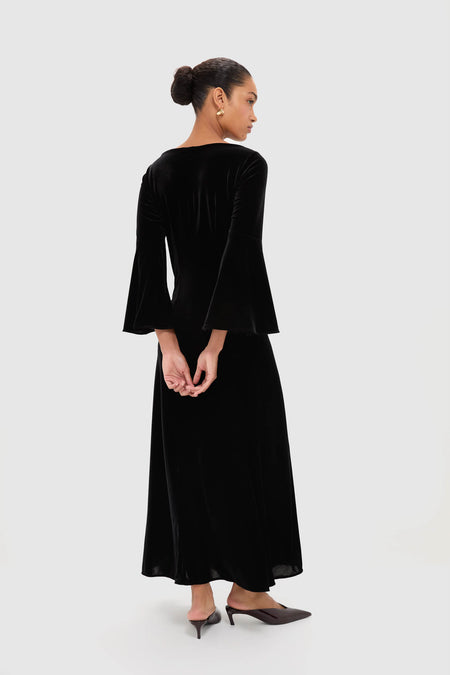 Woman in Accademia Black Velvet Bell Sleeve Catherine Maxi Dress, showcasing classic elegance with flared sleeves and lace yoke, styled with effortless sophistication.
