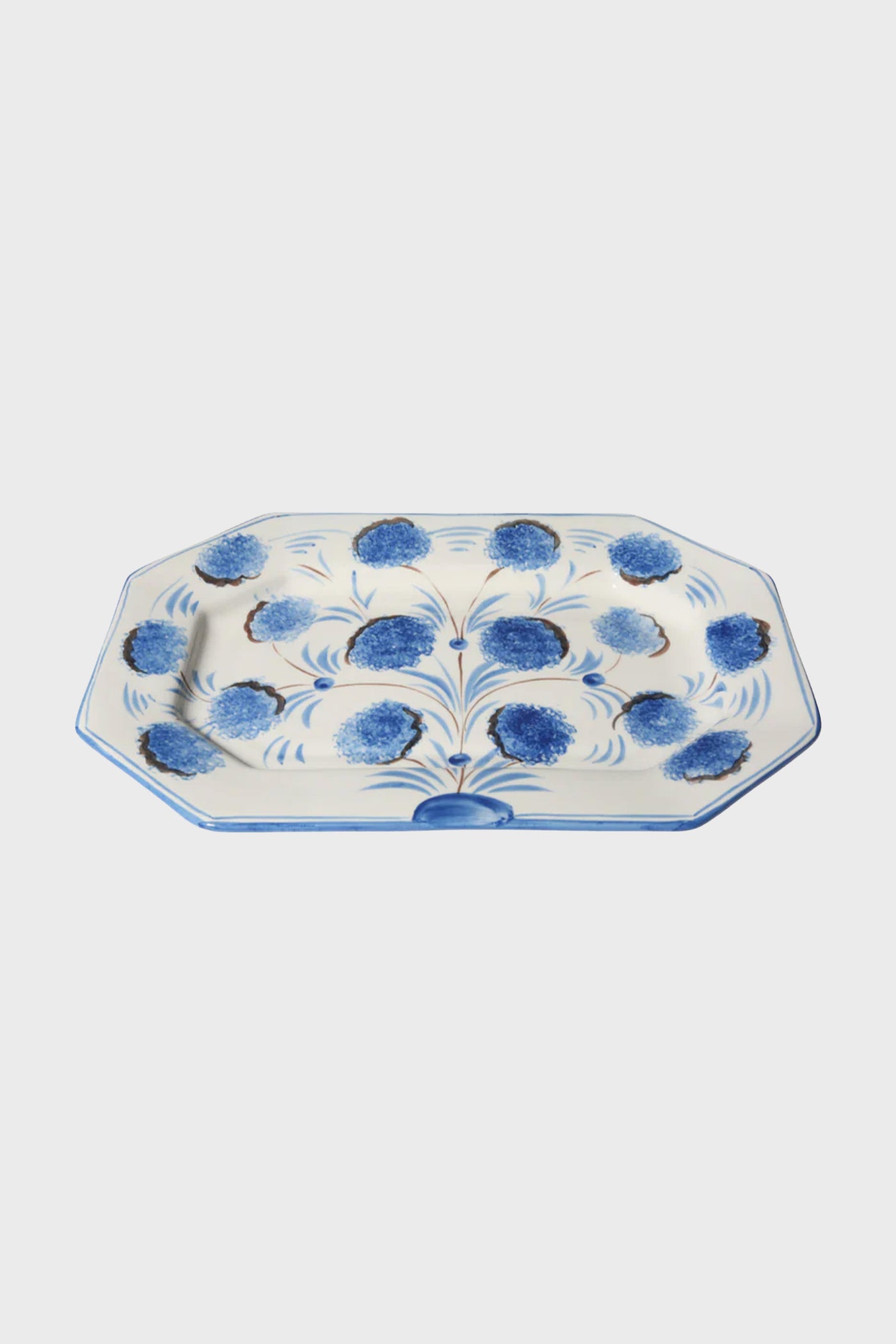 The Carolina Irving & Daughters Blue Flower Octagonal Platter features a hand-painted ceramic design with blue floral patterns and brown accents, perfect as handmade tableware.