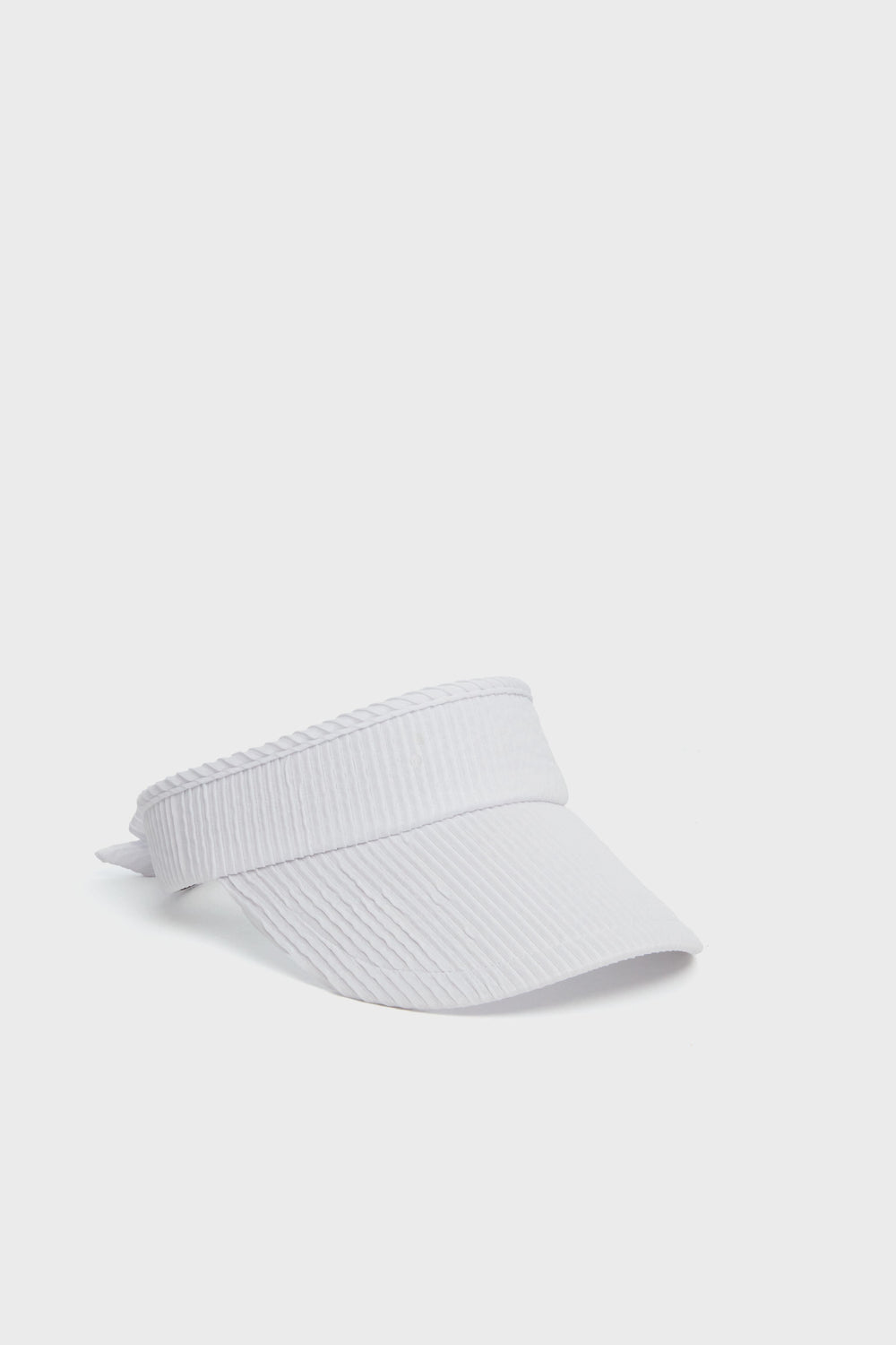 A sleek Lele Sadoughi white ribbed visor cap, crafted from a ruched poly blend for comfort and style, featuring an adjustable back strap.